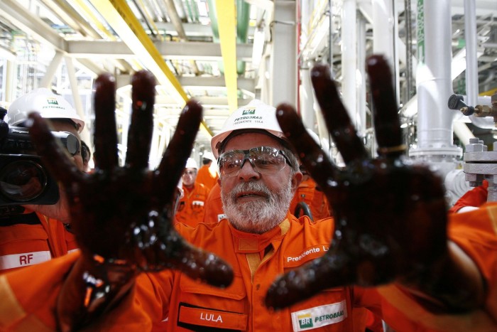 Lula poses with his hands covered in oil at a Petrobras event in 2010