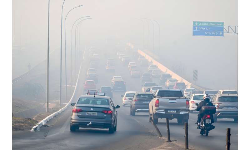 Vehicles are engulfed in smoke from the fire affecting the Brasilia National Park in Brasilia on September 16, 2024