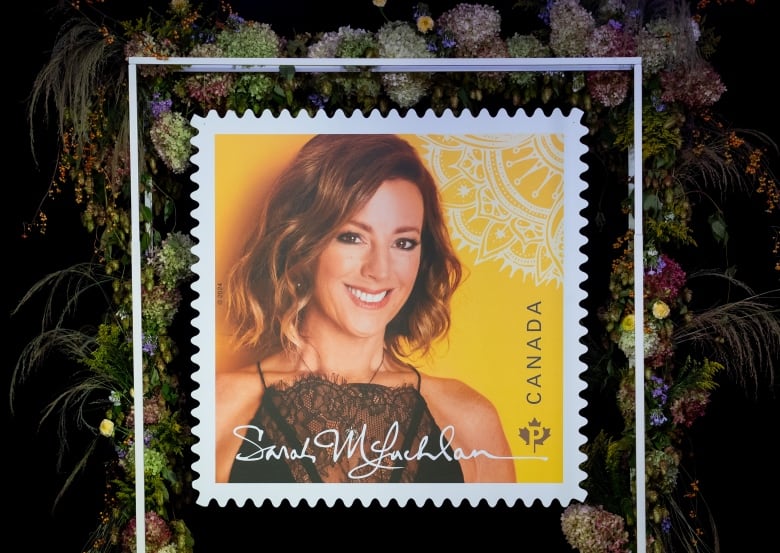 A stamp featuring a woman smiling before a yellow background.