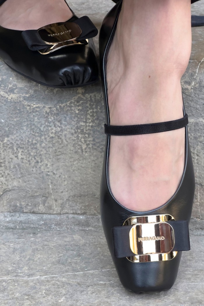 A close-up of someone’s feet, wearing buckled shoes, walking down stone steps