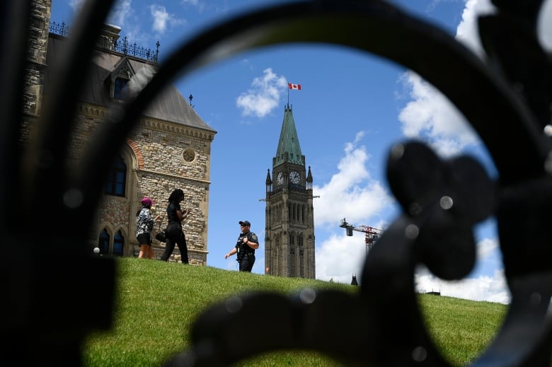 Centre Block’s Peace Tower is seen behind as a Parliamentary Protective Services officer walks on Parliament Hill in Ottawa.