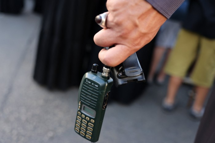 A man holds a walkie talkie device after he removed the battery during the funeral 