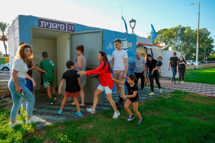 People in Nahariya, northern Israel, take cover as a siren warns of incoming rockets fired from Lebanon on Thursday