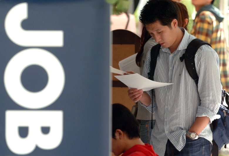 A man looks at a job ad at a job fair.