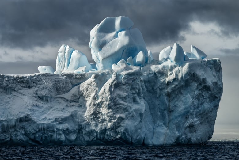 Smaller icebergs on a big flat iceberg against a dark background