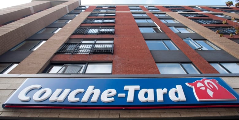 An upwards angle showing the Couche-Tard logo on a building and the sky beyond. 