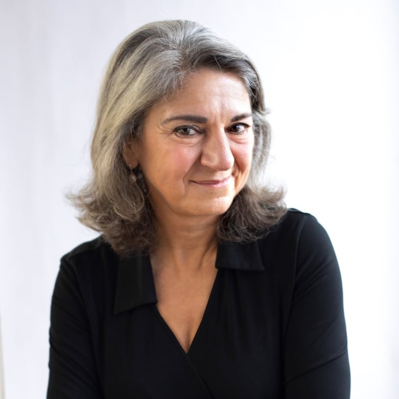 A woman in a black shirt wears a slight smile while posing for a portrait.