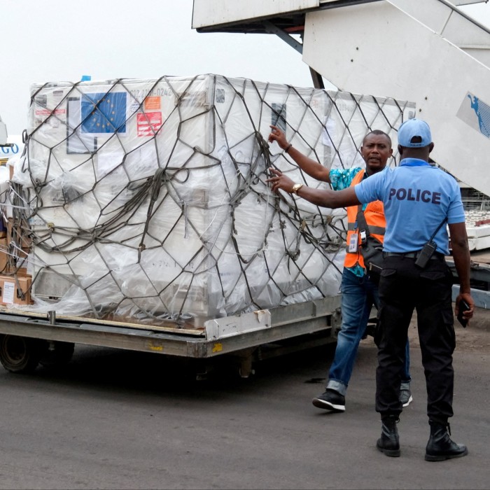 A security agent talks with a worker as he prepares to transport mpox vaccines as first batches arrive at N’Djili International Airport in Kinshasa, Democratic Republic of Congo