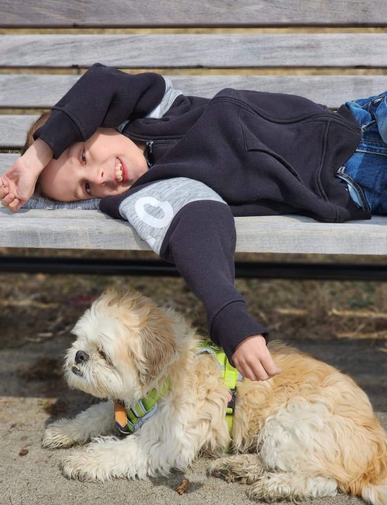 Child laying on a bench with a dog. 