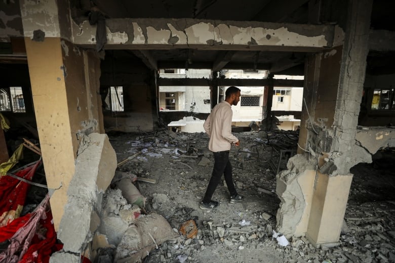 A man inspects rubble in a ruined building. 