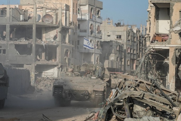 Israeli soldiers drive past destroyed buildings in Rafah in the Gaza Strip