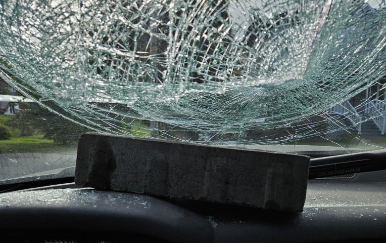 A brick shattered the car windshield and rest on top of the dashboard 