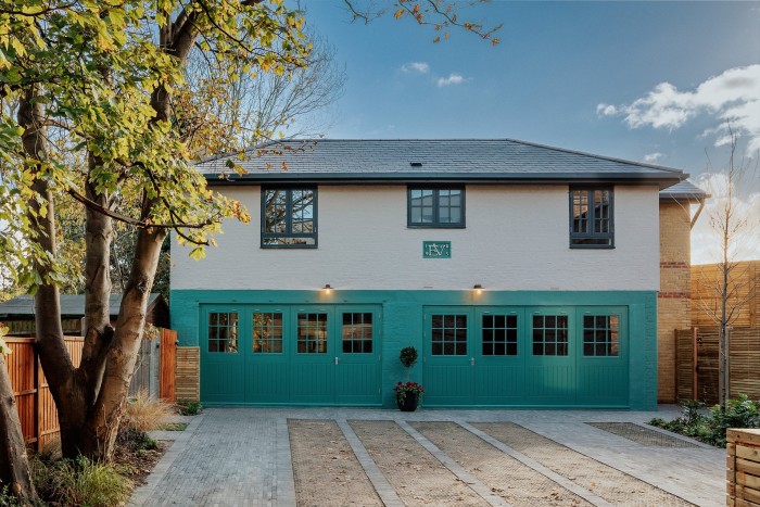 A two-storey Victorian coach house that has been restored; the top half of the brick exterior is painted white, the bottom half is blue, with half-glazed wooden doors running across the whole width of the property