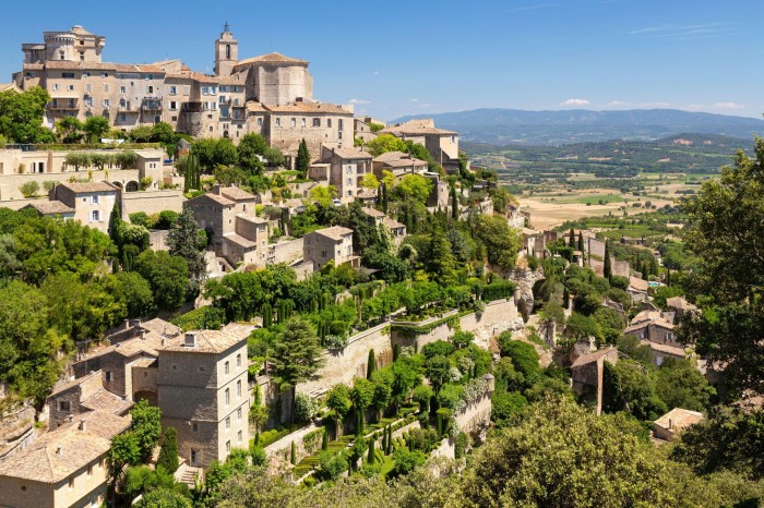 A stone hillside village overlooking a green landscape under a blue sky