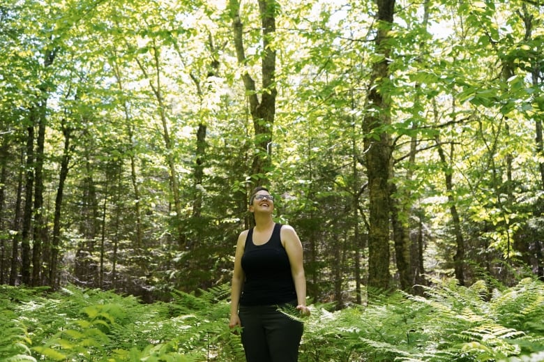 Megan de Graaf, forest program director at Community Forests International, stands among green ferns at Robinson Conservation Forest in New Brunswick.