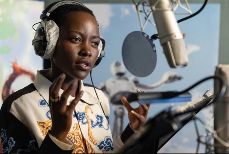 Lupita Nyong'o in a voice booth talking into a microphone