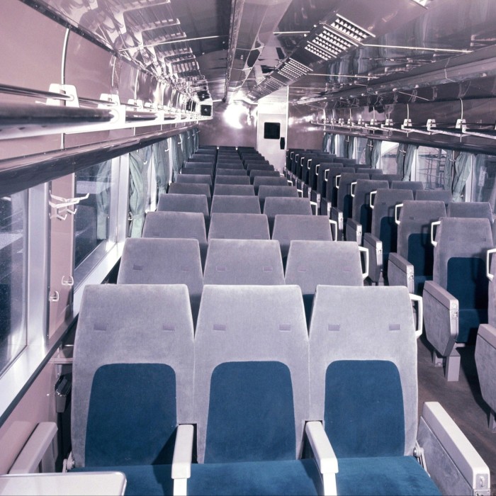 Multiple rows of three-wide train seats in the interior of a train carriage 