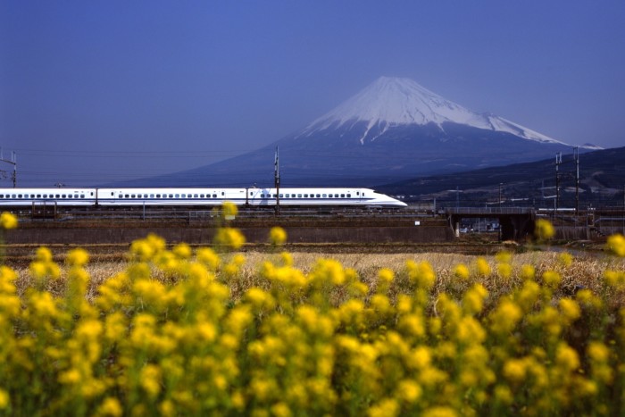 A train passes in front of a snow-capped mountain