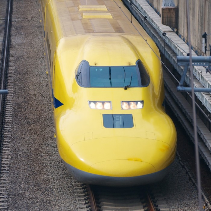 A yellow train passes through a station