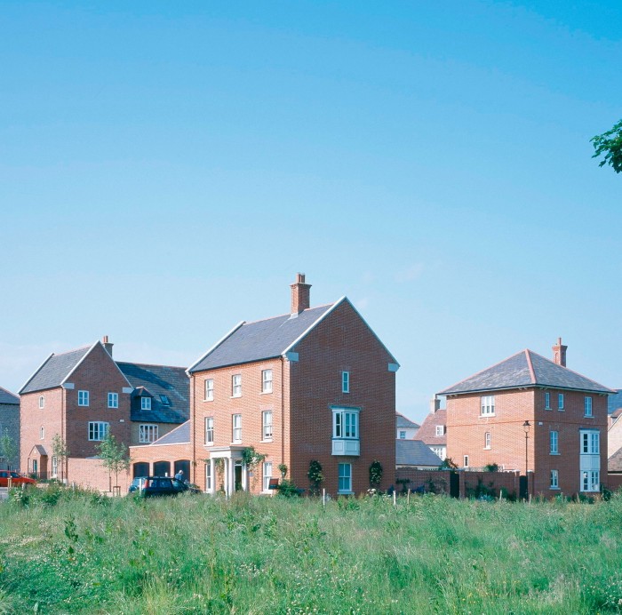 A colour photo of modern houses built of red brick against a sunny blue sky