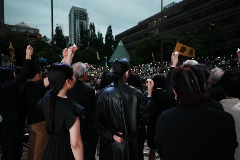 A group of people hold up artificial candles.