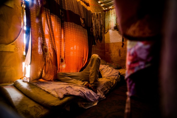 Resting on a pile of mattresses in a makeshift wooden hut built onto the roof of a house, a Yemeni man rests amid the chaos of Djibouti’s slums