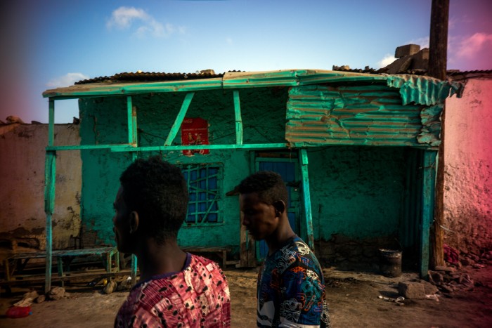 Two men pass a brightly painted Ethiopian restaurant as they aimlessly walk the town’s streets in search of casual work