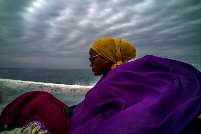 Crossing the sea from Obock, two women wrapped in colourful scarves travel in a small, fibreglass speedboat