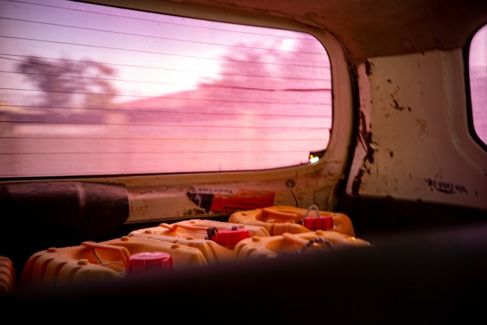 View from the inside of a vehicle showing multiple yellow jerry cans in the back