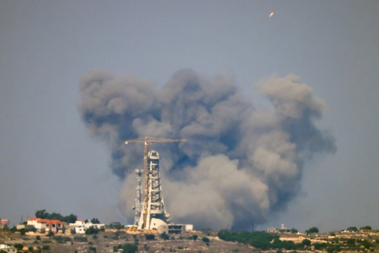 A rocket is launched from southern Lebanon as smoke billows from behind the Em e Nour Shrine after an Israeli Air Force air strike, amid cross-border hostilities between Hezbollah and Israel, as seen from northern Israel, September 28, 2024. 