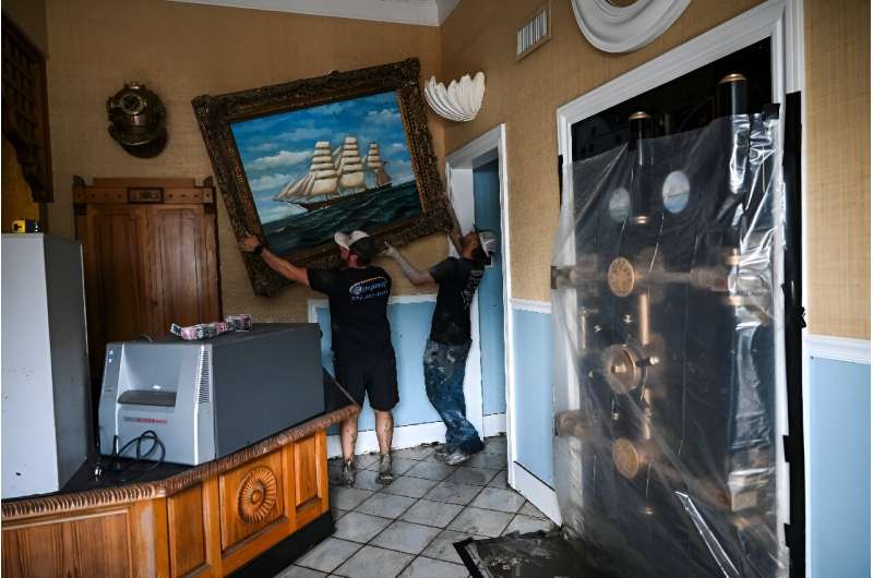 Workers clean the damaged property of a bank after Hurricane Helene rumbled through Cedar Key, Florida