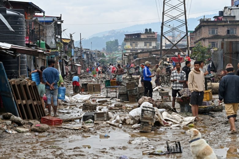 People stand in the street near their belongings that were swept away by flooding. 