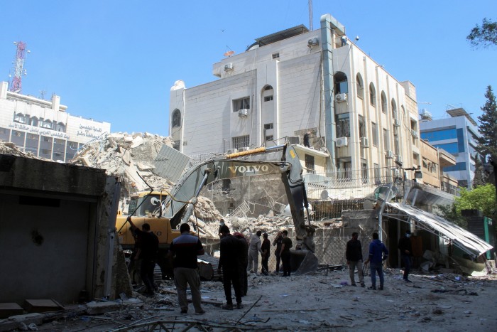 An excavator clears rubble from the site of the consulate