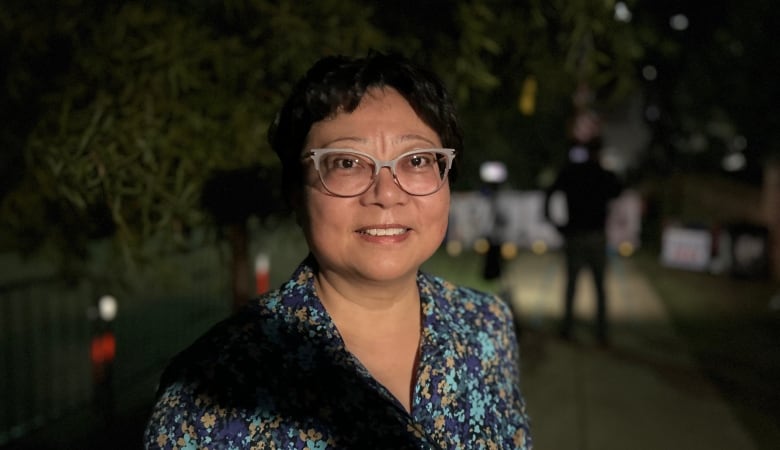 A woman standing outside at night smiles for the camera.