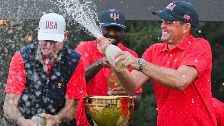 United States team member Keegan Bradley, right, sprays captain Jim Furyk, center, and teammates with champagne after winning the Presidents Cup over the International Team at the Royal Montreal Golf Club in Montreal, Sunday, Sept. 29, 2024. (Graham Hughes/The Canadian Press via AP) 