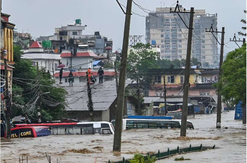 Kathmandu residents climb on the rooftops as their neighbourhood is submerged in flood waters after the Bagmati River overflowed following heavy monsoon rains