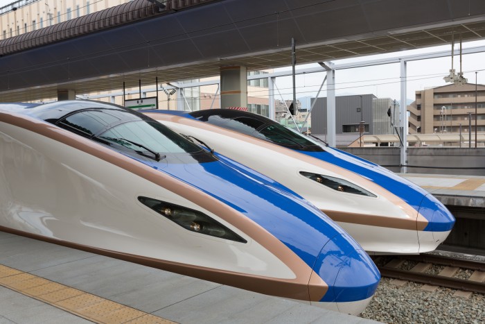 The stylish and elongated nose cones of two trains sit side by side at a rail station