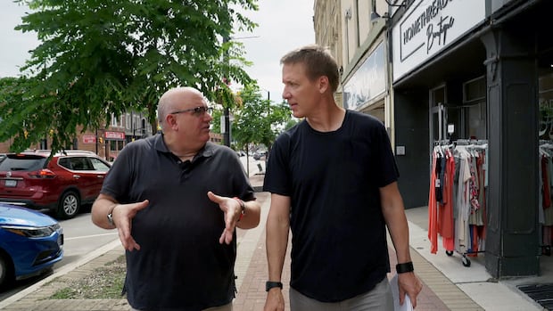 A reporter walk down a street listening to another man