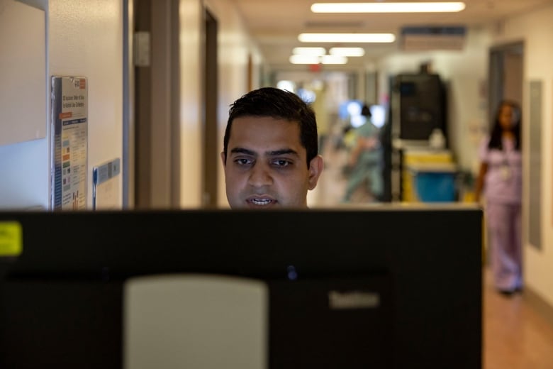 Dr. Amol Verma, a clinician-scientist at St. Michael’s Hospital who helped lead the creation and testing of CHARTwatch, stands at a computer.