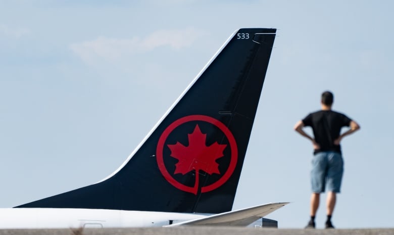 A person watches an Air Canada plane at an airport in Montreal.