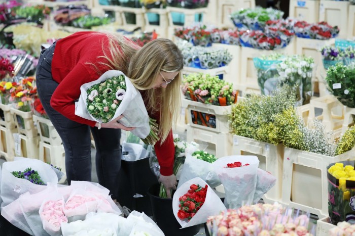 Shoppers examine flowers at Covent Garden Flower Market in London