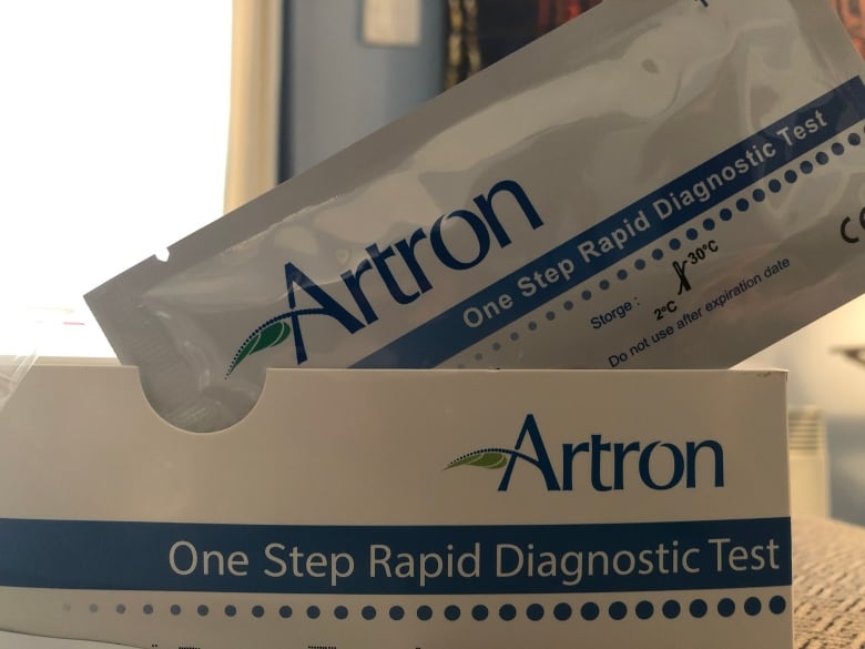 A COVID rapid test sits on top of the box. It is branded Artron.