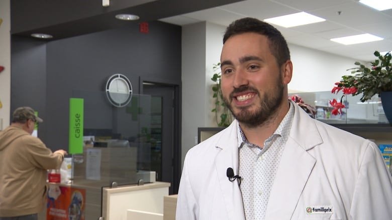 A man smiles at camera. He is wearing a white coat with a small logo that reads 'familiprix'