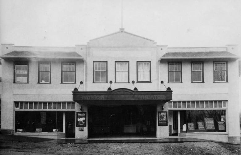 The black-and-white photograph shows an old two-storey movie theatre.