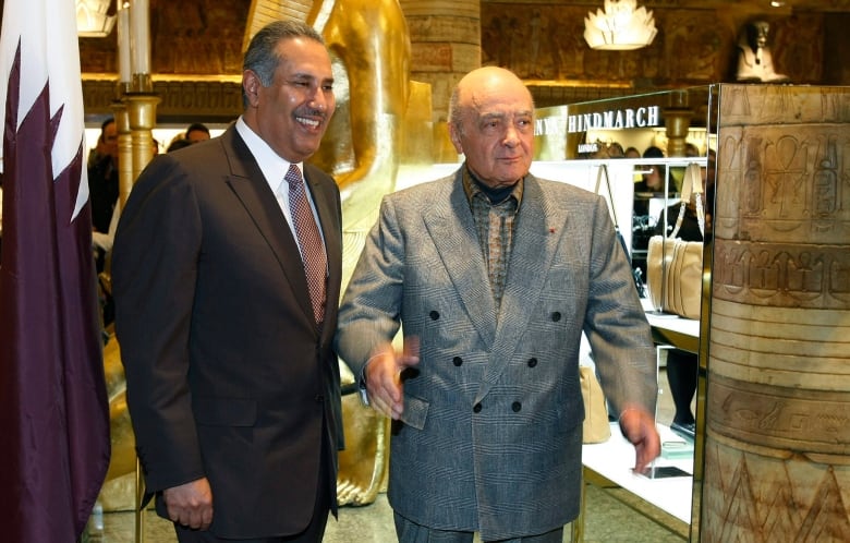 Two people stand among displays in a luxury department store.