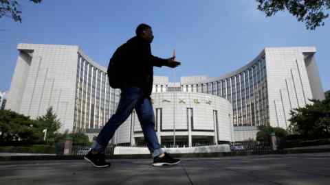 A man walks past the headquarters of the People's Bank of China in Beijing