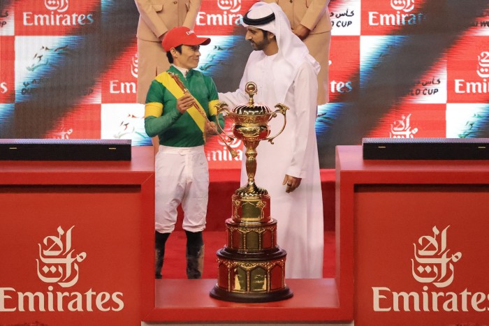 Sheikh Hamdan bin Mohammed al-Maktoum presents jockey Yuga Kawada with a trophy at the Dubai racing World Cup