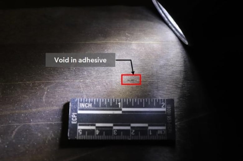 A photo of a grey material with a title that says "void in adhesive."