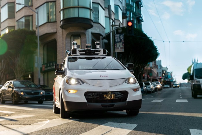 A self-driving car from Cruise equipped with multiple sensors and cameras on its roof driving through an urban intersection