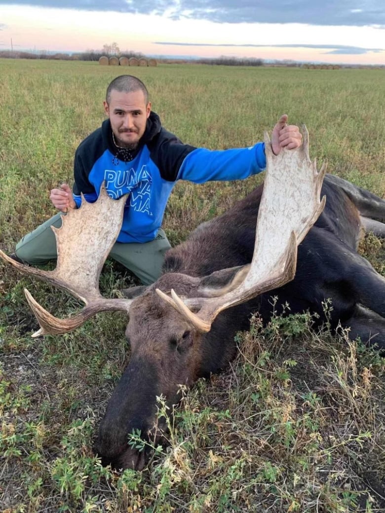 A man next to a dead moose.